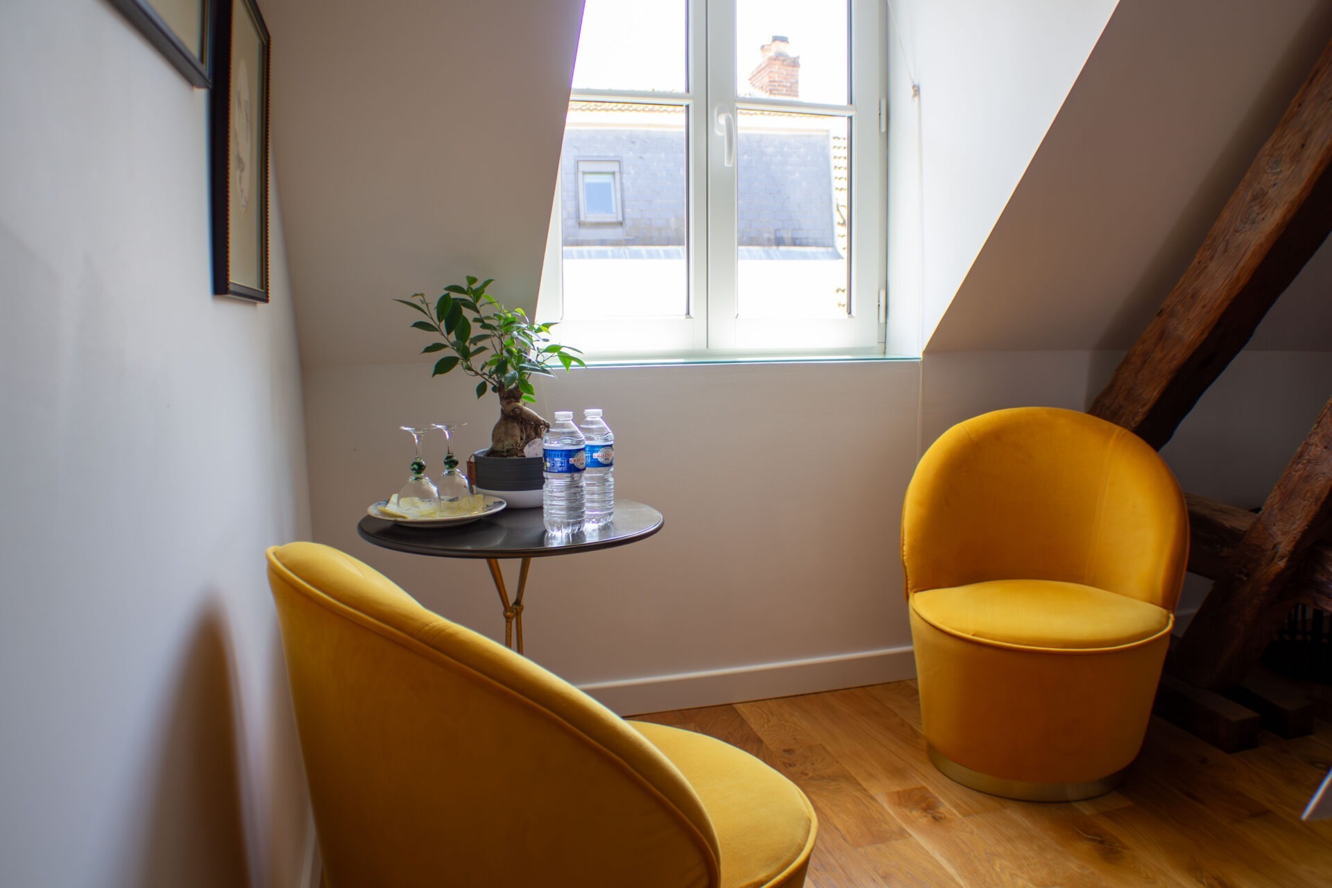 Petit coin salon avec deux fauteuils jaune autour d'une petite table ronde à côté de la fenêtre
