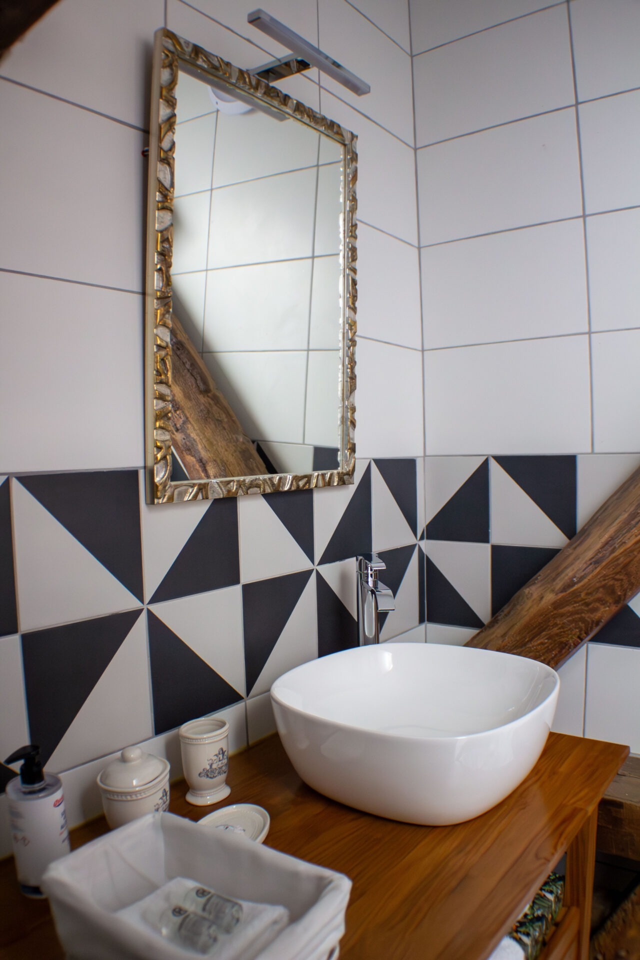 Salle de bain en carrelage noir et blanc et poutre en bois apparente